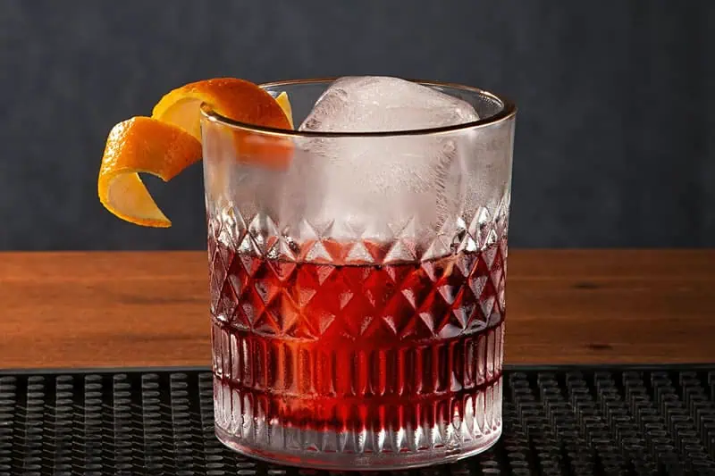 Vaso con cóctel Negroni servido con hielo y rodaja de naranja