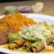 Flautas de res doradas servidas con lechuga, crema, queso y salsa mexicana