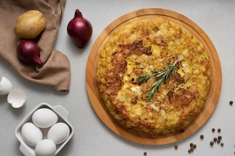 Tortilla española con ingredientes a su alrededor