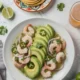 Tazón de aguachile de camarón con un plato de tostadas y vaso de cerveza