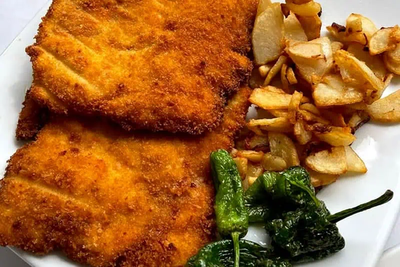 Cachopo Asturiano: Un Clásico de la Cocina del Norte de España Plato de cachopo asturiano con papas y pimientos del piquillo