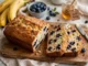 Pan de plátano con arándanos recién horneado sobre una mesa blanca marmoleada