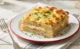 Pastel de papa con jamón cocido y queso fundido recién horneado con superficie gratinada y porción servida.
