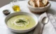 Plato hondo con crema de espárragos decorada con puntas de espárrago, crema y crutones sobre superficie de mármol blanco