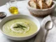 Plato hondo con crema de espárragos decorada con puntas de espárrago, crema y crutones sobre superficie de mármol blanco
