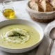 Plato hondo con crema de espárragos decorada con puntas de espárrago, crema y crutones sobre superficie de mármol blanco
