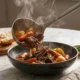 Plato hondo de estofado de res casero con papas, zanahorias y perejil fresco