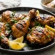 Piernas y muslos de pollo a la parrilla con piel dorada, limón y perejil