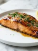 Salmón Glaseado Con Miel y Ajo: la cena de 25 minutos que siempre luce como de restaurante Filete de salmón glaseado con miel y ajo, con perejil y ajonjolí, sobre una superficie de mármol blanco