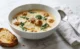 Sopa de Salchicha Toscana Cremosa: el tazón que abraza en los días fríos Tazón de sopa de salchicha toscana cremosa con papas y col rizada, con parmesano y pan tostado sobre una superficie de mármol blanco