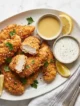 Tenders de Pollo Caseros: crujientes y tiernos a la vez Plato con aderezos y tenders de pollo