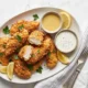 Tenders de Pollo Caseros: crujientes y tiernos a la vez Plato con aderezos y tenders de pollo